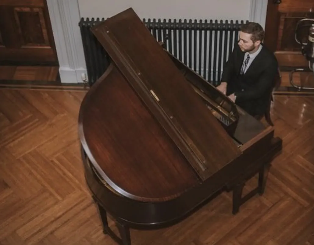 Finn at a baby grand in a panelled room, seen from above